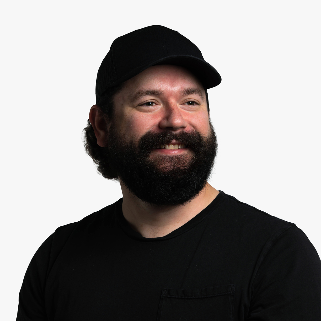 Daniel Boggs, a while male in his late 30s with dark brown hair and a full beard, wearing a black t-shirt and black trucker hat.