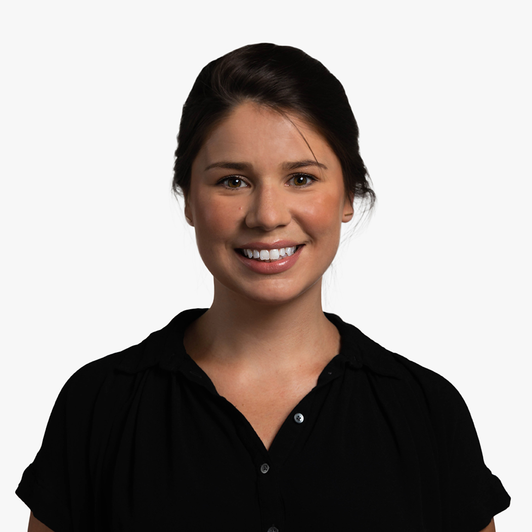 Lizzy Cederberg, a white woman in her thirties with dark brown hair pulled back into a bun, wearing a black short-sleeved button down shirt, looking off to the right and smiling.