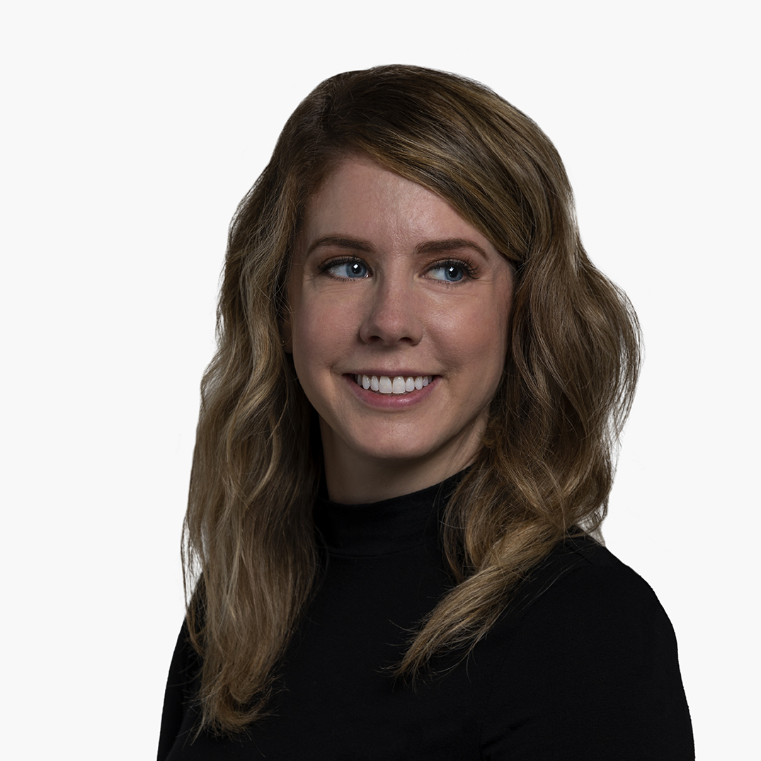 Sarah Greene, a white woman with wavy light brown hair and blue eyes, wearing a black turtle neck, smiling, and looking to her left.