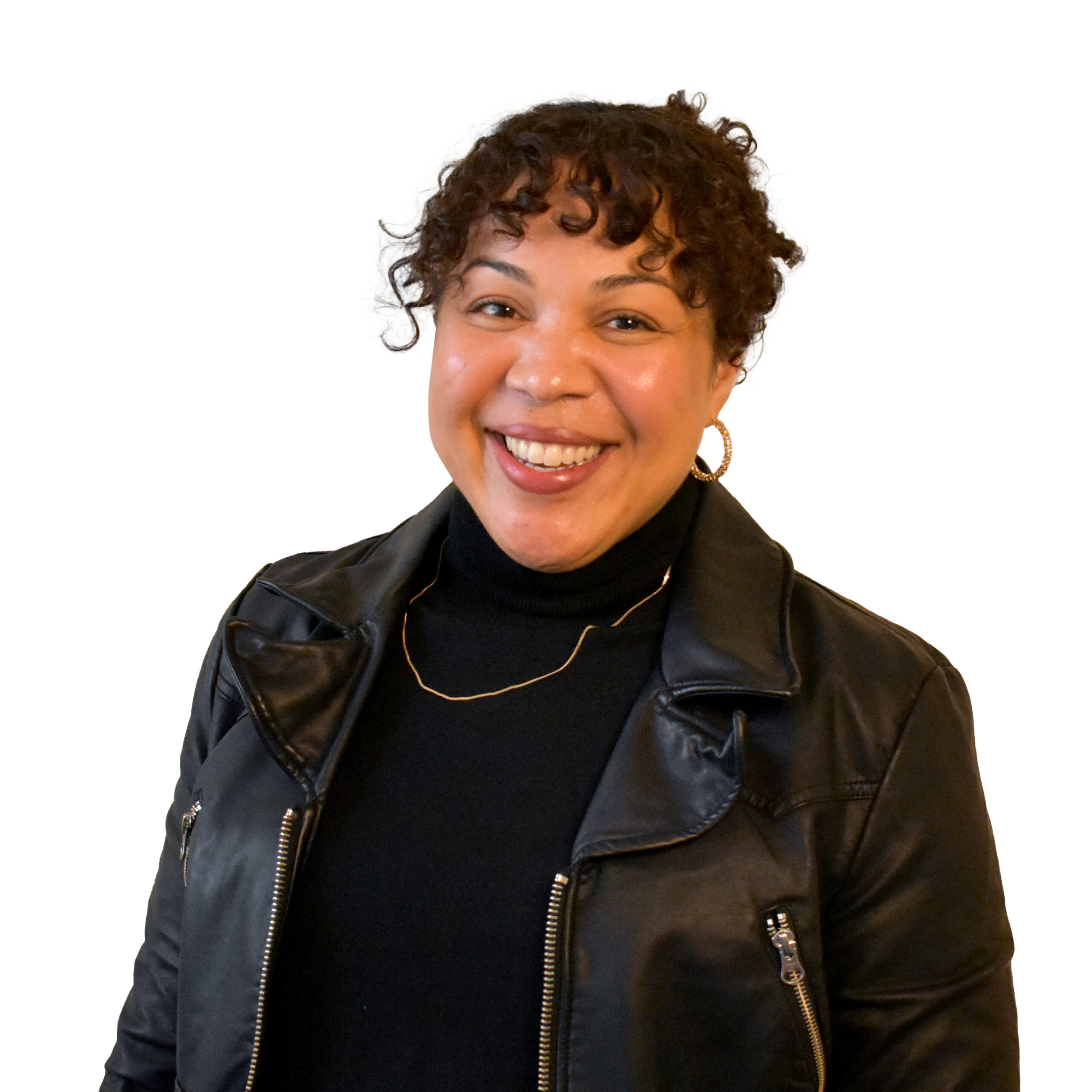 Liz Ott, a Black woman laughing with curly brown hair tied up wearing black turtleneck and (vegan) leather jacket.